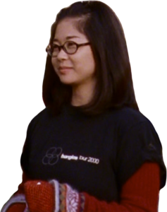 Lane wears a black t-shirt with white text reading "Bangles Tour 2000," layered over a long-sleeved red top.